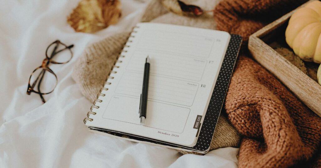 Post Traumatic Stress Disorder (PTSD) Treatment vs Rehabilitation Open planner with pen, glasses, and cozy blankets for PTSD treatment.
